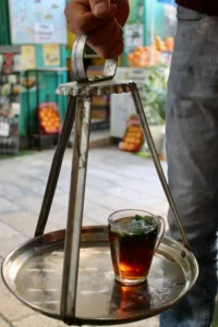 Arab Herbal Tea: Traditional deep herbal tea served in a glass cup on an Ottoman-style Tepsi tray