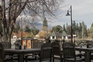 Steamer A musician playing guitar at an outdoor cafe in Queenstown with autumn trees and mountains in the background.Wharf, Queenstown
