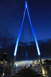 Symmetrical night view looking down the illuminated Wynyard Crossing bridge with glowing blue pylons in Auckland.