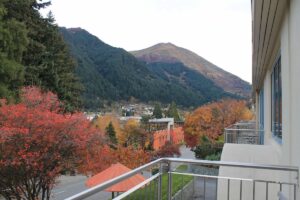 utumn view of Te Tapu-nui (Queenstown Hill) with orange trees and hotel balconies in the foreground.