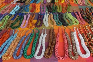Dozens of vibrant, multi-colored beaded necklaces hanging in rows at an Ecuadorian market stall